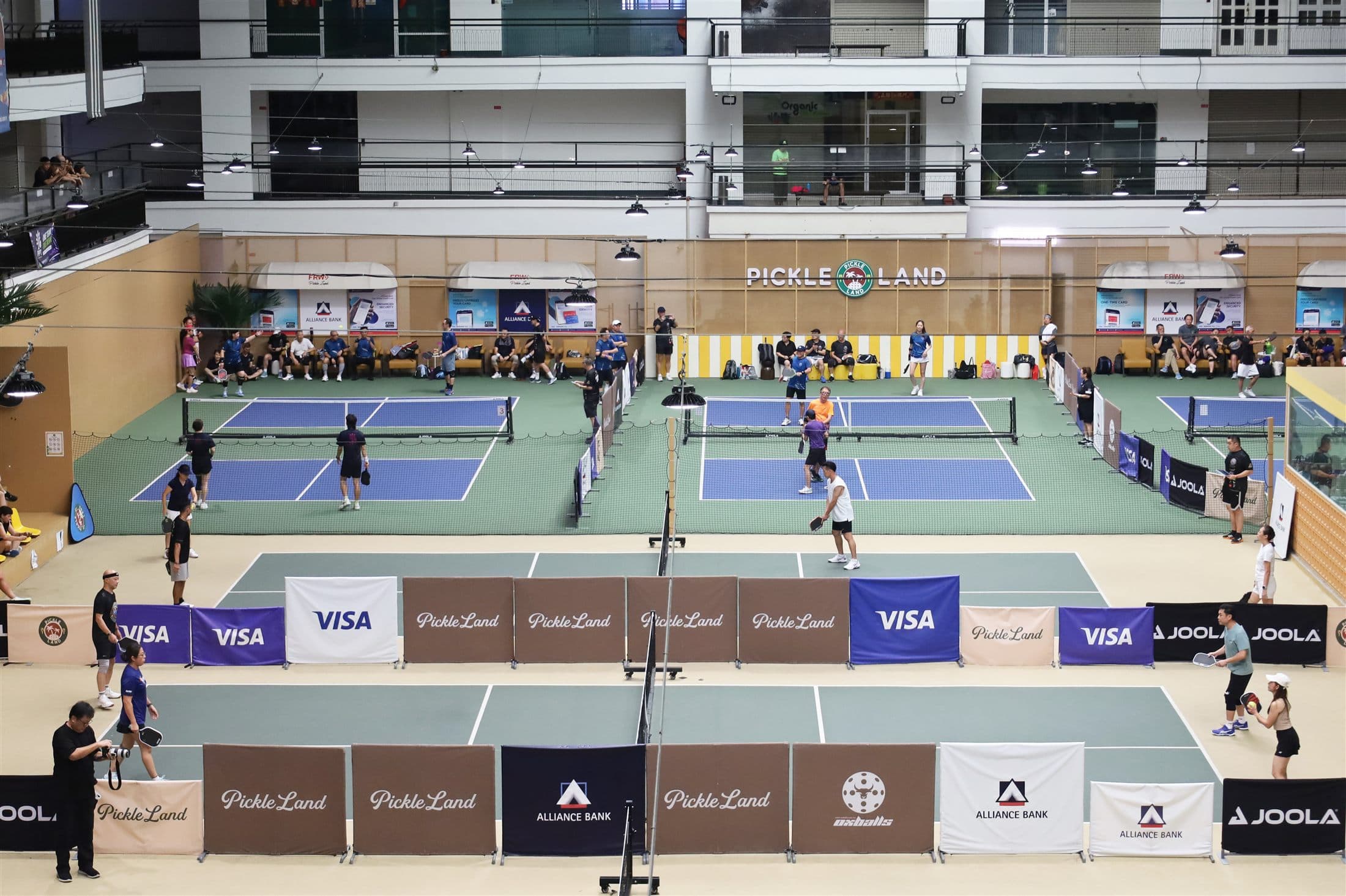 Wide active view of Pickleland's indoor courts during play
