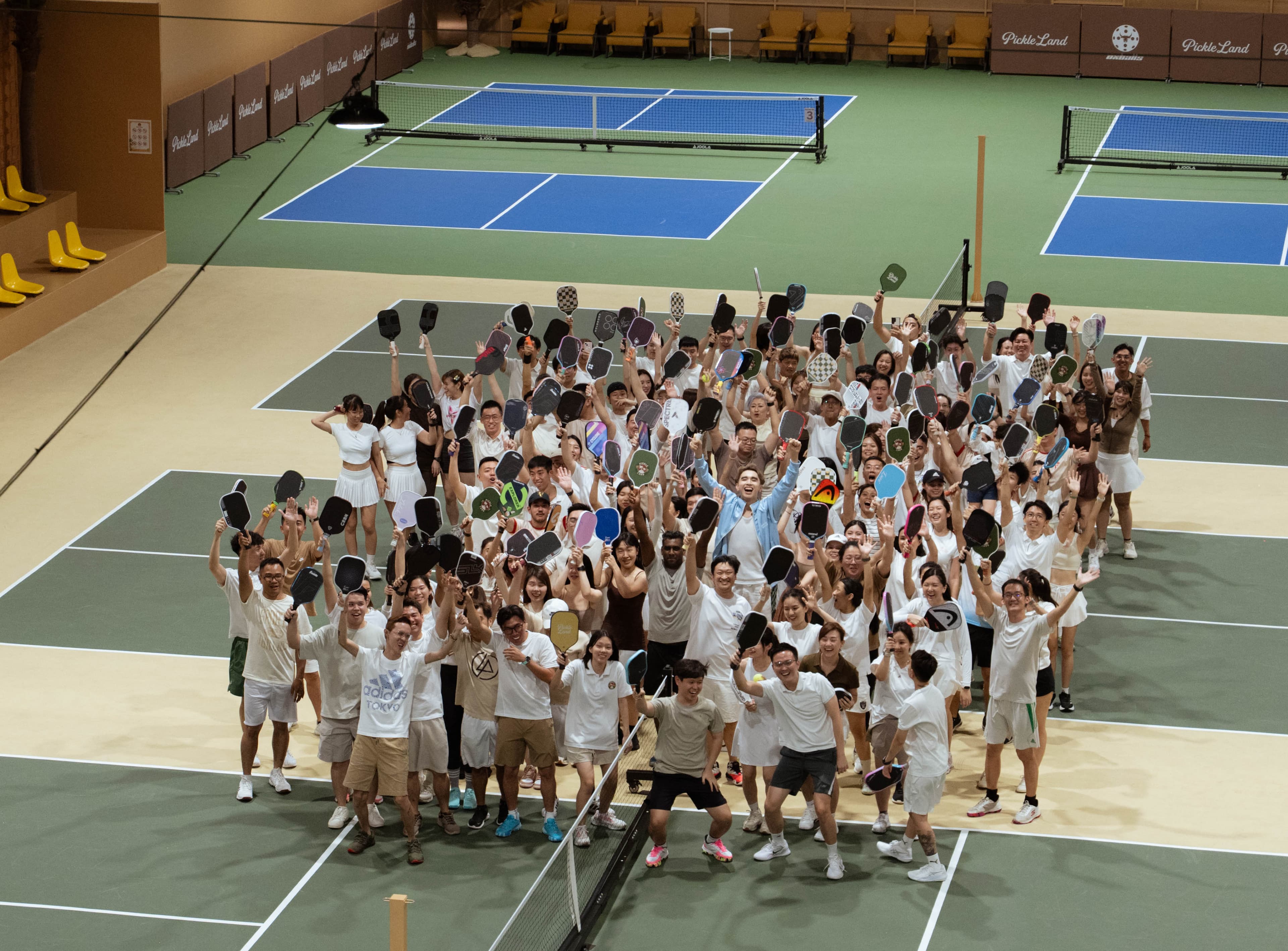 Full cast and crowd celebrating with paddles raised on the Pickle Land courts